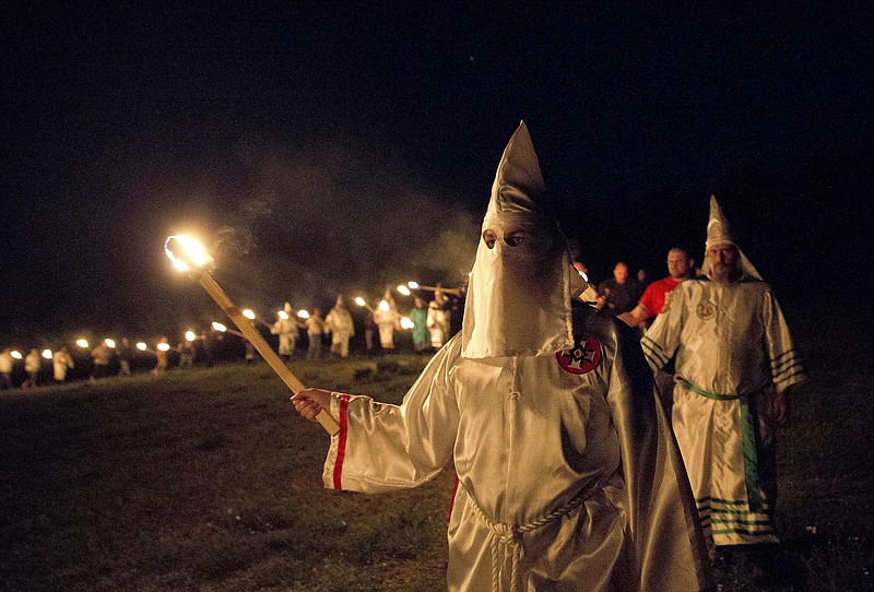 In this Saturday, April 23, 2016 photo, members of the Ku Klux Klan participate in cross burnings after a "White Pride," rally, in rural Paulding County near Cedar Town, Ga. The Ku Klux Klan is trying to raise its hooded head 150 years after it was founded following the Civil War. Born in the ashes of the smoldering South after the Civil War, the Ku Klux Klan died and was reborn before losing the fight against civil rights in the 1960s. (AP Photo/John Bazemore)
            