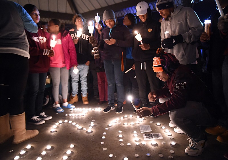 In this Dec. 18, 2015, file photo, Zack Dobson, bottom right, lights candles to honor his slain brother, Zaevion Dobson, at Sam E. Hill Park in Knoxville. Zaevion Dobson, a Tennessee high school football player who was shot to death while shielding two girls from gunfire, will receive the Arthur Ashe Courage Award at the July 2016 ESPYs ceremony.