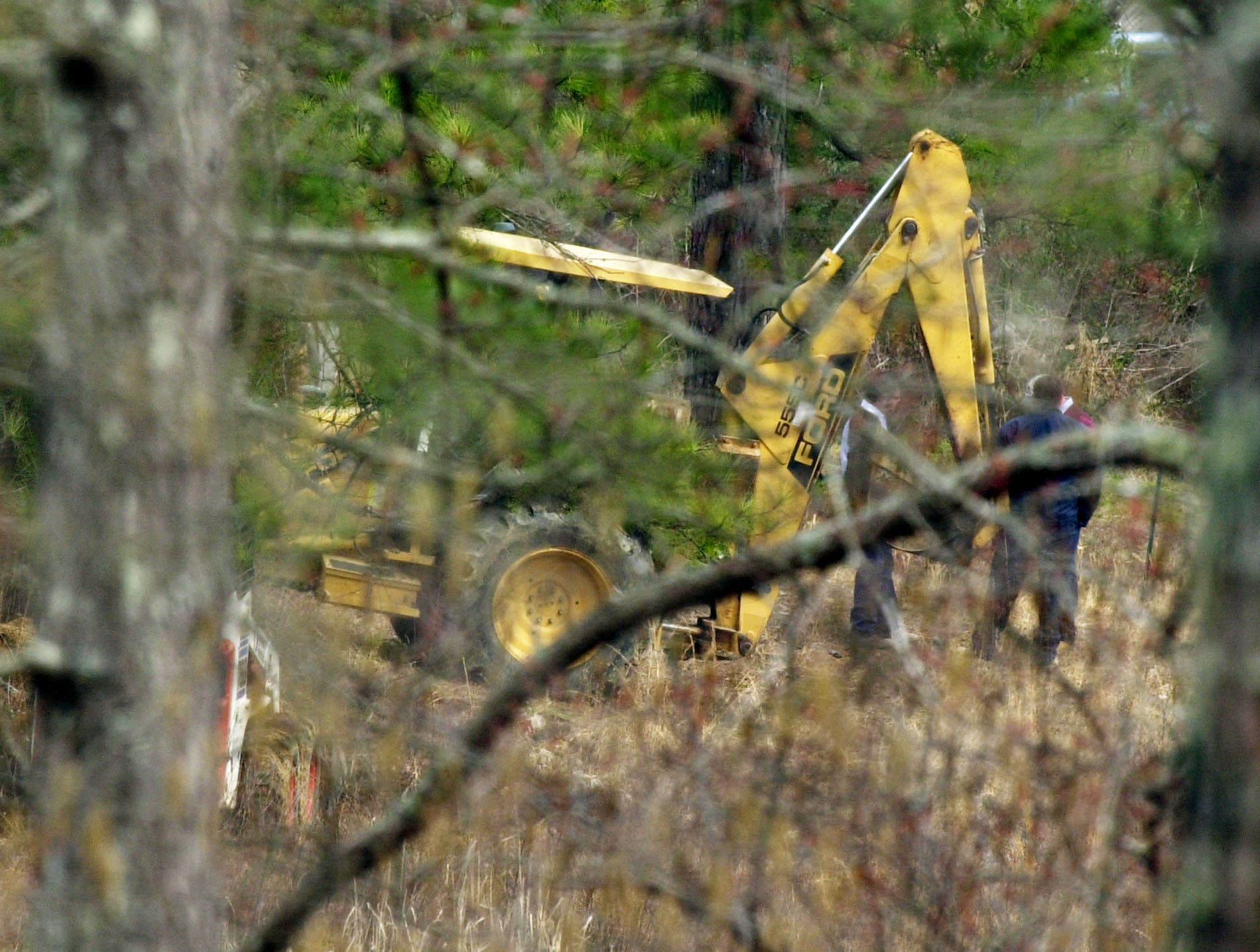 **FILE** Officials with a Bobcat and a backhoe dig behind the home of Ray Brent Marsh, 28, outside of Noble, Ga., in this Feb. 19, 2002, file photo. Several revelations were made in recently unsealed depositions in a federal lawsuit that went to trial in March 2004 in the case of a former northwest Georgia crematory operator accused of dumping 334 bodies and passing off concrete dust as people's remains. The revelations include: Heavy machinery was used to remove some bodies, two sets of remains were misidentified and given to the wrong families and an official says the state's chief medical examiner left the crime scene for long periods to spend time with a subordinate. Defense lawyers for Ray Brent Marsh plan to use the testimony to prove that authorities botched the Feb. 2002 investigation. (AP Photo/Ric Feld, File)