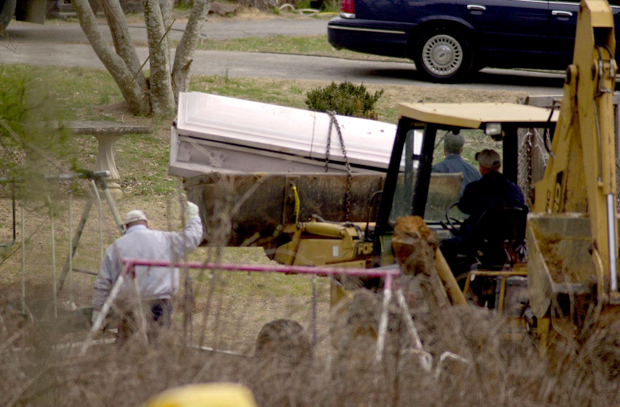 Tri-State Crematory investigators remove a casket from the backyard of Brent Marsh's family home Tuesday, February 19, 2002. More remains were found today as the investigation continues.