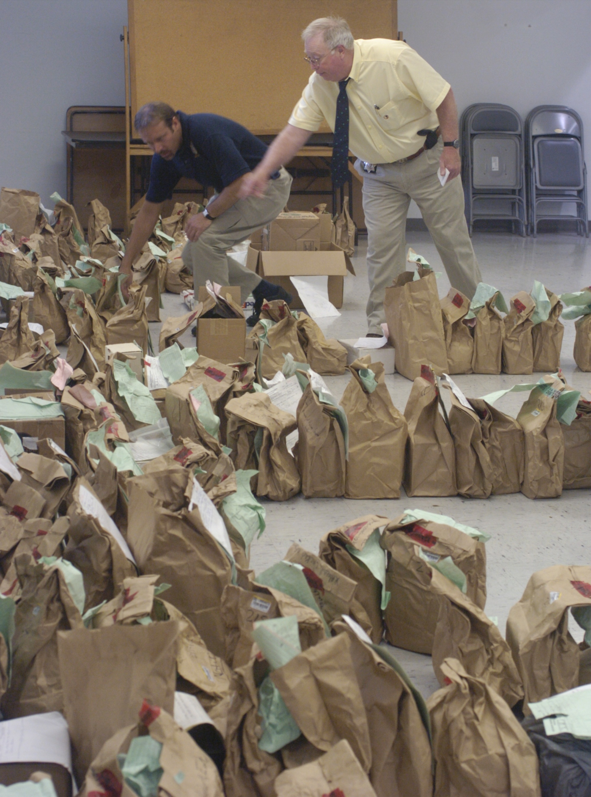 Staff Photo by John Rawlston                James Harris of the GBI, left, and Bill Cason of the Walker County Sheriff's Office search for an evidence bag Wednesday morning at the Walker County Civic Center to return to a family of a victim of the Tri-State Crematory  scandal.
