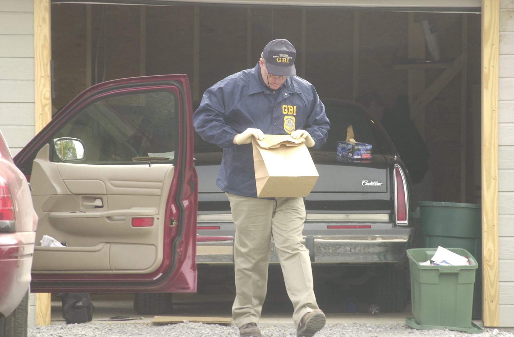 Staff Photo by Kathleen Cole     A GBI investigator searches the vehicles and garage at the Marsh residence at the Tri-State Crematory in Noble, Georgia, Tuesday, February 19, 2002. More human remains were found on the property Tuesday.