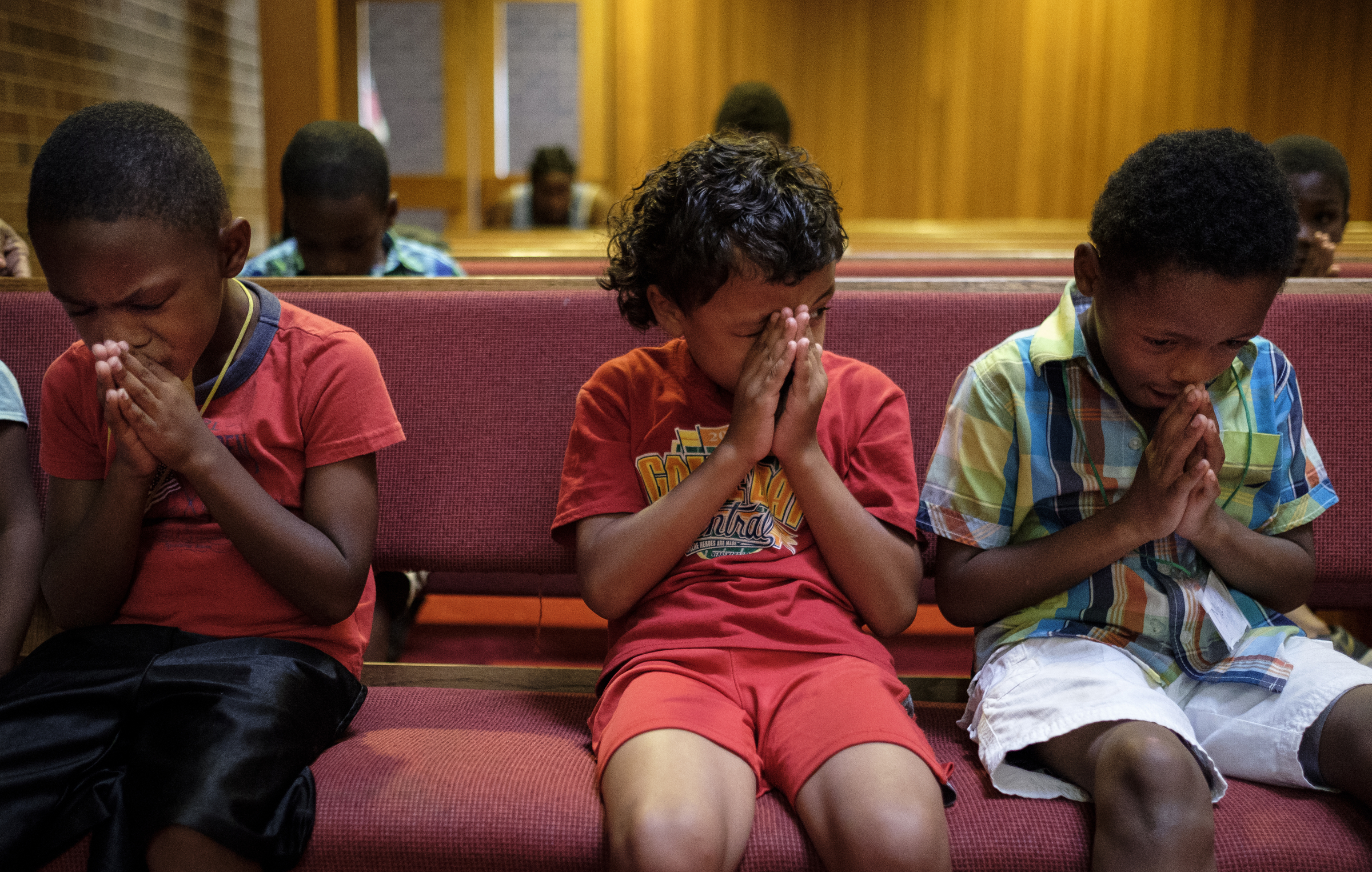 Leo Jenkins, center, peeks from behind his hands as he bows his head for prayer with Justin Longfort, left, and Malik robinson at a camp for kids operated by Gloria Griffith at Renaissance Presbyterian Church on Tuesday, June 28, 2016, in Chattanooga, Tenn. Griffith has operated the camp for 5 years, but because of health problems, Griffith expects that she will have to end the camp this month if she can't find someone to take her place.