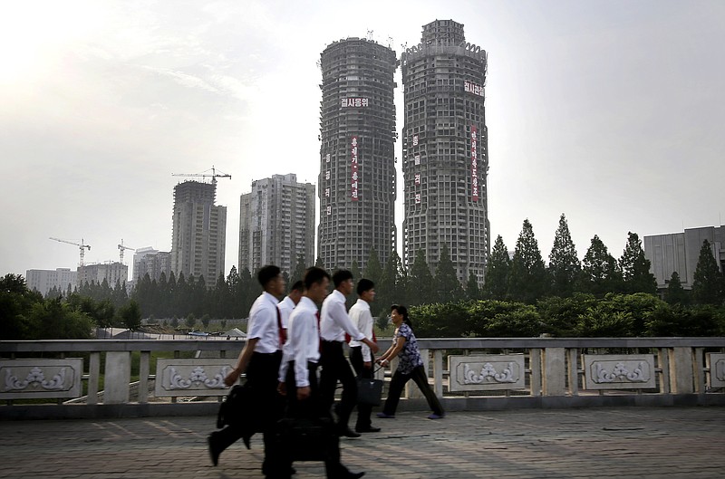 
              In this June 27, 2016, photo, North Korean men and women walk past buildings under construction on “Ryomyong Street,” in Pyongyang, North Korea. Hoping to show the world his country is doing just fine despite sanctions and outside pressure over its nuclear weapons program, North Korean leader Kim Jong Un has put his soldier-builders to work on yet another major project - a series of apartments and high-rises that are once again changing the Pyongyang skyline. “Ryomyong Street,” is to have the country's tallest apartment building, at 70 stories, along with a 50-story building and a handful of smaller ones in the 30-40 story range. (AP Photo/Wong Maye-E)
            