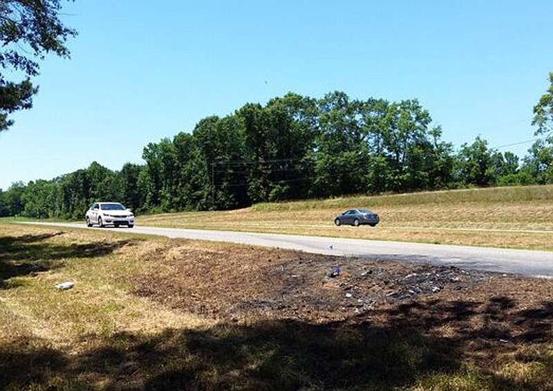 Cars pass charred ground, Tuesday, June 7, 2016, remnants at the scene of a fatal traffic accident in rural Tuscaloosa County, Ala. James Halsell Jr., a former NASA astronaut who flew on five space shuttle missions, is is charged with murder after an early-morning car wreck Monday, June 6, killed two young sisters on the lonely stretch of highway in Alabama.