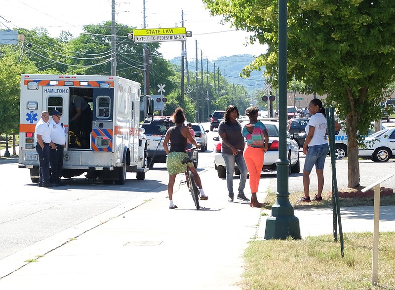 Onlookers and emergency medical personnel stand by after a man was shot in the leg Thursday morning around 10 a.m. in Alton Park. Police are not sure if he was shot there, or just drove to the parking lot after being shot.