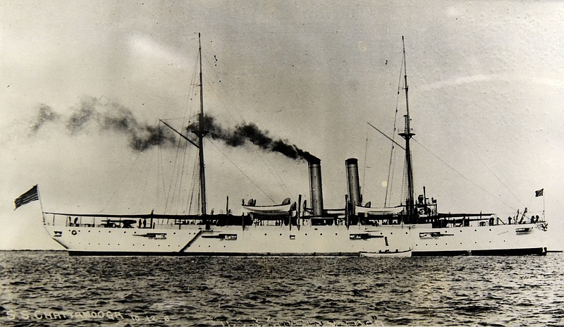 An old photograph of the USS Chattanooga is displayed next to a bell from the ship, stamped with a date of 1904, on display at the National Medal of Honor Museum at Northgate Mall.