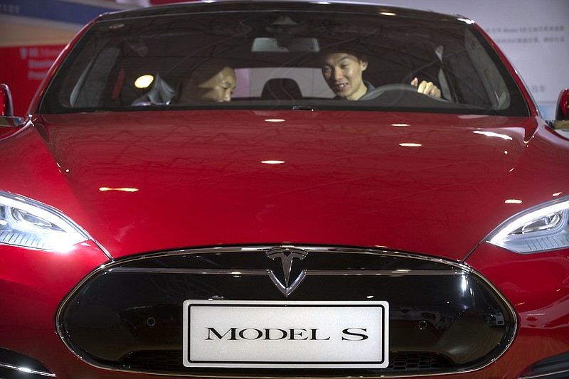 
              FILE - In this Monday, April 25, 2016, file photo, a man sits behind the steering wheel of a Tesla Model S electric car on display at the Beijing International Automotive Exhibition in Beijing. Federal officials say the driver of a Tesla S sports car using the vehicle’s “autopilot” automated driving system has been killed in a collision with a truck, the first U.S. self-driving car fatality. The National Highway Traffic Safety Administration said preliminary reports indicate the crash occurred when a tractor-trailer made a left turn in front of the Tesla at a highway intersection. NHTSA said the Tesla driver died due to injuries sustained in the crash, which took place on May 7 in Williston, Fla. (AP Photo/Mark Schiefelbein, File)
            