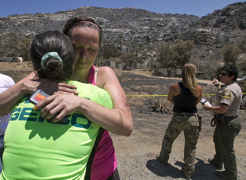 
              Neighbors Leann Mitsui, left, and Stephanie Riverburgh hugged after they and two other women discovered the burned remains of two victims of the Potrero, Calif., fire, Wednesday, June 29, 2016. San Diego County Sheriff's Department spokeswoman Jan Caldwell said the unidentified man and woman were found Wednesday near a boulder in Potrero, about 45 miles east of San Diego. The property had been under mandatory evacuation orders after a fire began on June 19 and has since spread to nearly 12 square miles. (John Gibbins/The San Diego Union-Tribune via AP)
            