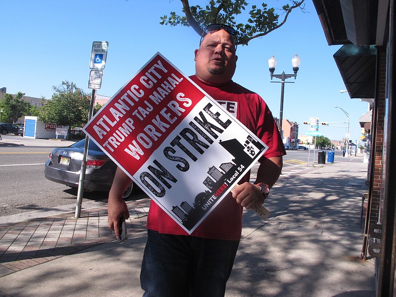 
              A casino worker carries a picket sign on Thursday June 30, 2016 in Atlantic City N.J. as contract talks between his union, Local 54 of Unite-HERE and the Trump Taj Mahal were underway to try to prevent a threatened Friday strike. The union earlier in the day had reached agreement with the four other casinos it had threatened to strike. (AP Photo/Wayne Parry)
            