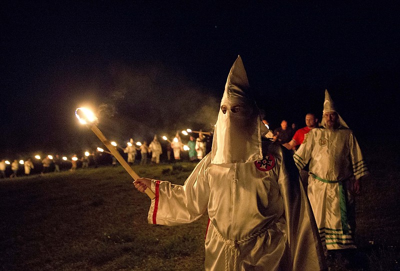 
              In this Saturday, April 23, 2016 photo, members of the Ku Klux Klan participate in cross burnings after a "white pride" rally in rural Paulding County near Cedar Town, Ga. Born in the ashes of the smoldering South after the Civil War, the KKK died and was reborn before losing the fight against civil rights in the 1960s. Membership dwindled, a unified group fractured, and one-time members went to prison for a string of murderous attacks against blacks. Many assumed the group was dead, a white-robed ghost of hate and violence. (AP Photo/John Bazemore)
            