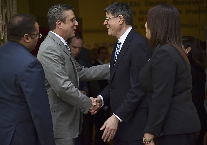 
              FILE - In this May 9, 2016, file photo, U.S. Treasury Secretary Jacob Lew, right, shakes hands with Puerto Rico's Governor Alejandro Garcia Padilla before touring Eleanor Roosevelt Elementary School in San Juan, Puerto Rico. Puerto Rico faces a historic default of $2 billion Friday, July 1, as the U.S. territory prepares to enter unchartered waters under the guidance of a newly enacted federal control board to oversee the island’s finances amid a dire economic crisis. (AP Photo/Carlos Giusti, File)
            