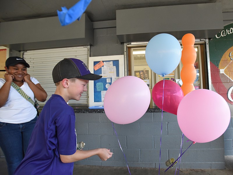 Cooper Barnes pops one of the balloons holding $20 bills, donated to his family by teenagers working the concession stand at Harrison Recreation during baseball season. The donation was to help fund therapy-dog training for Cooper's German shepherd.
