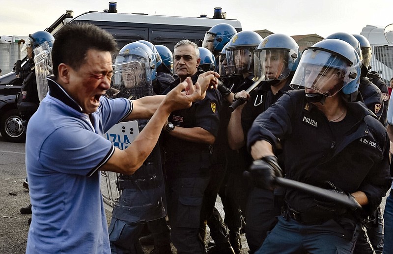 
              In this picture taken Thursday, June 30, 2016, italian Police officers in riot gears push back a protester during clashes with members of the local Chinese community in Sesto Fiorentino, on the outskirts of Florence Italy. Members of the Chinese community have clashed against police in a protest against what they say are excessive controls over their companies. Police lashed back with batons leaving several Chinese injured and bloodied on the ground. In interviews on Italian Television, Chinese protesters complained the Italian government continues to do raids on their businesses frequently fining them unfairly for infractions of Italian laws. (Maurizio Degli'Innocenti/ANSA Via AP)
            