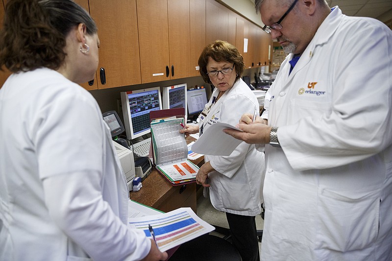 Infection prevention nurses Kanae Gilliland, left, and Velda Kilgore, center, work with clinical administrator Ted Nelson to review charts and check for patients with catheters at Erlanger Hospital on Friday, June 24, 2016, in Chattanooga, Tenn. The trio are a team responsible for ensuring that catheters are properly placed to reduce the chance of infection.