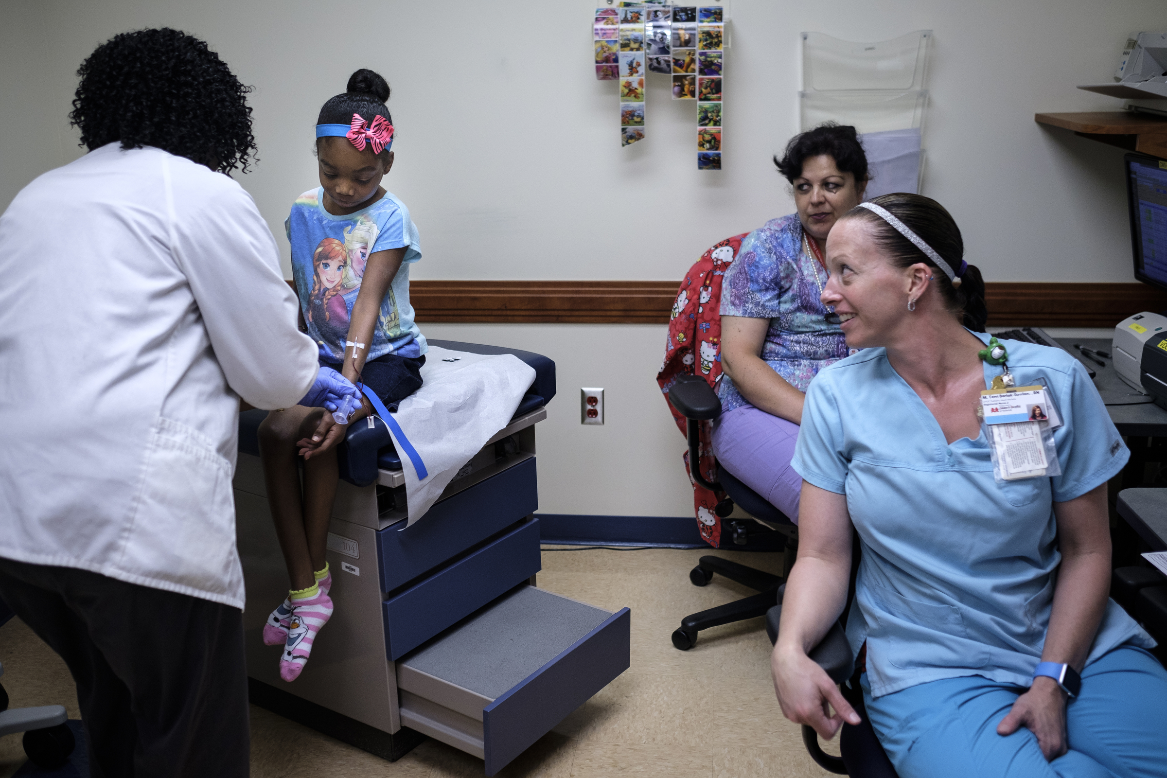 Terri Bartek, right, and Manuela Iliescu talk with Ahmya Calloway, center, as phlebotomist Vivian Samuel, left, draws blood during one of Ahmya's regular checkups to monitor her new heart at Vanderbilt Children's Hospital on Thursday, June 30, 2016, in Nashville, Tenn. Almost two months after receiving a heart and kidney transplant, Ahmya was told she could transition to once-weekly checkups and return home to Chattanooga.