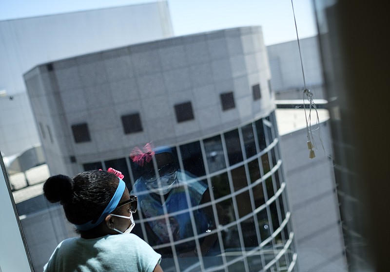 Ahmya Calloway wears a surgical mask to protect from contagious illnesses as she looks out a waiting room window before an appointment to monitor her new kidney at Vanderbilt Children's Hospital on Thursday, June 30, 2016, in Nashville, Tenn. The anti-rejection drugs Ahmya must take for the rest of her life to ensure her body does not reject her transplanted heart or kidney also weaken her immune system.