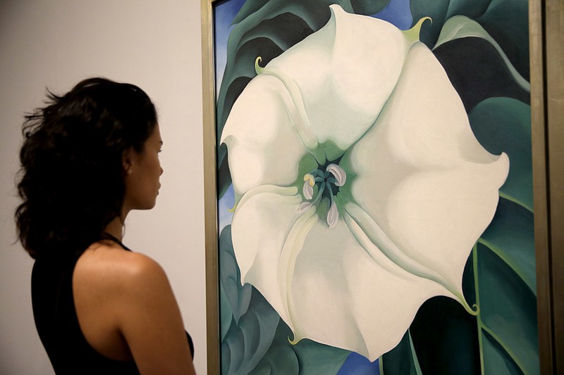 
              A Tate Modern representative poses for photographs next to "Jimson Weed/White Flower No.1" by American artist Georgia O'Keeffe at a press launch for her retrospective exhibition of over 100 works at the Tate Modern gallery in London, Monday, July 4, 2016. O'Keeffe is one of the iconic American artists of the 20th century, but an exhibition of more than 100 works opening this week at Tate Modern is her biggest-ever show outside the United States. (AP Photo/Matt Dunham)
            