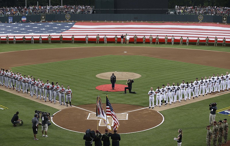 Miami Marlins and Atlanta Braves players line the base paths during the national anthem prior to a baseball game in Fort Bragg, N.C., Sunday, July 3, 2016. (AP Photo/Gerry Broome)