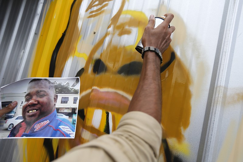 
              Artist Jo Hines spray paints a mural of Alton Sterling outside the Triple S convenience store in Baton Rouge, La., Wednesday, July 6, 2016. Sterling, 37, was shot and killed outside the store by Baton Rouge police, where he was selling CDs. (AP Photo/Gerald Herbert)
            