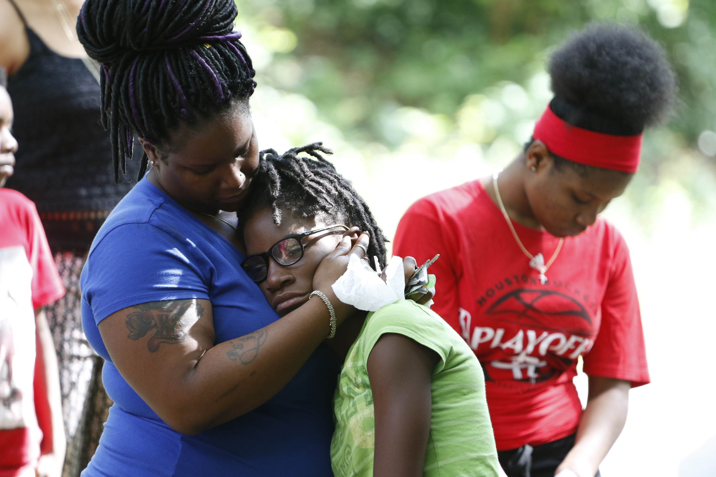 Rasheda Trimble, wife of Justin LaVon Trimble, consoles her daughters Diamond Trimble, 11, center, and Deja Trimble, 16, right, as they visit the scene where the late Justin LaVon Trimble lost control of his motorcycle and fatally struck a tree upon exiting the Wilcox Tunnel a month ago.