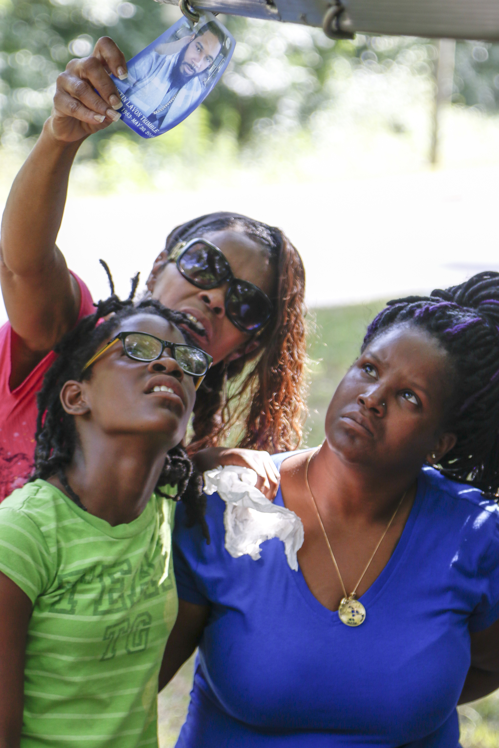 Staff Photo by Dan Henry / The Chattanooga Times Free Press- 7/7/16. Diamond Trimble, daughter, Justina Jones, mother, and Rasheda Trimble, wife, from left, look at a photo of the late Justin LaVon Trimble, who lost control of his motorcycle and fatally struck a tree upon exiting the Wilcox Tunnel a month ago.