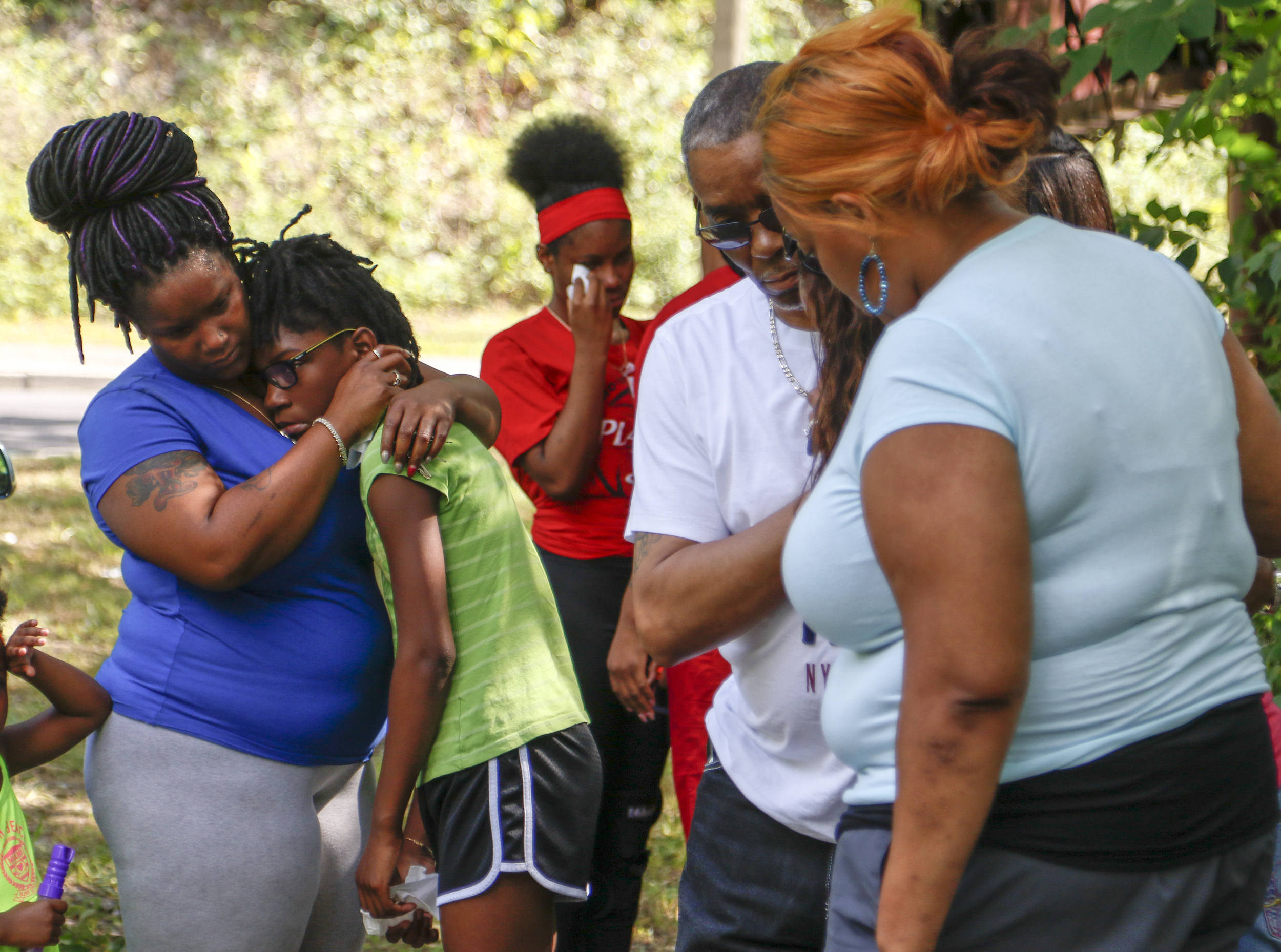 Staff Photo by Dan Henry / The Chattanooga Times Free Press- 7/7/16. Rasheda Trimble, wife of Justin, consoles her daughters Diamond Trimble, 11, center left, and Deja Trimble, 16, center right, as they and other family members visit the scene where the late Justin LaVon Trimble, lost control of his motorcycle and fatally struck a tree upon exiting the Wilcox Tunnel a month ago.