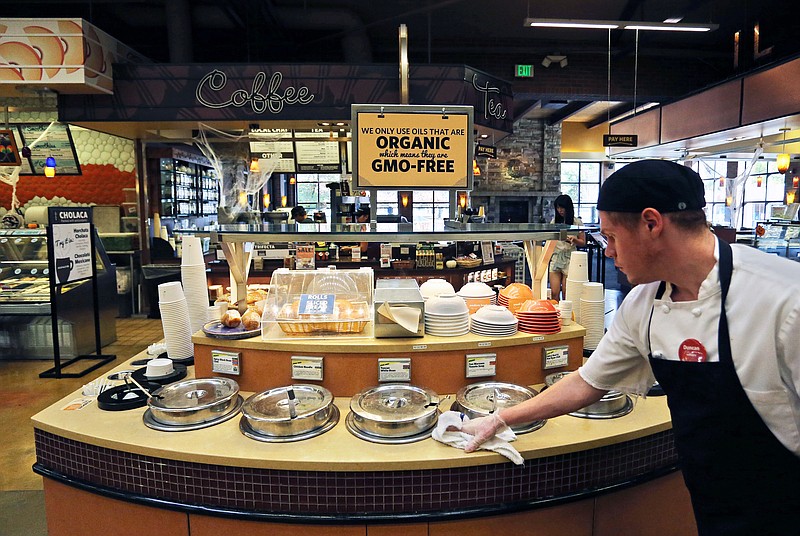
              FILE - In this Oct. 23, 2014 file photo, a grocery store employee wipes down a soup bar with a display informing customers of organic, GMO-free oils, in Boulder, Colo.  (AP Photo/Brennan Linsley, File)
            