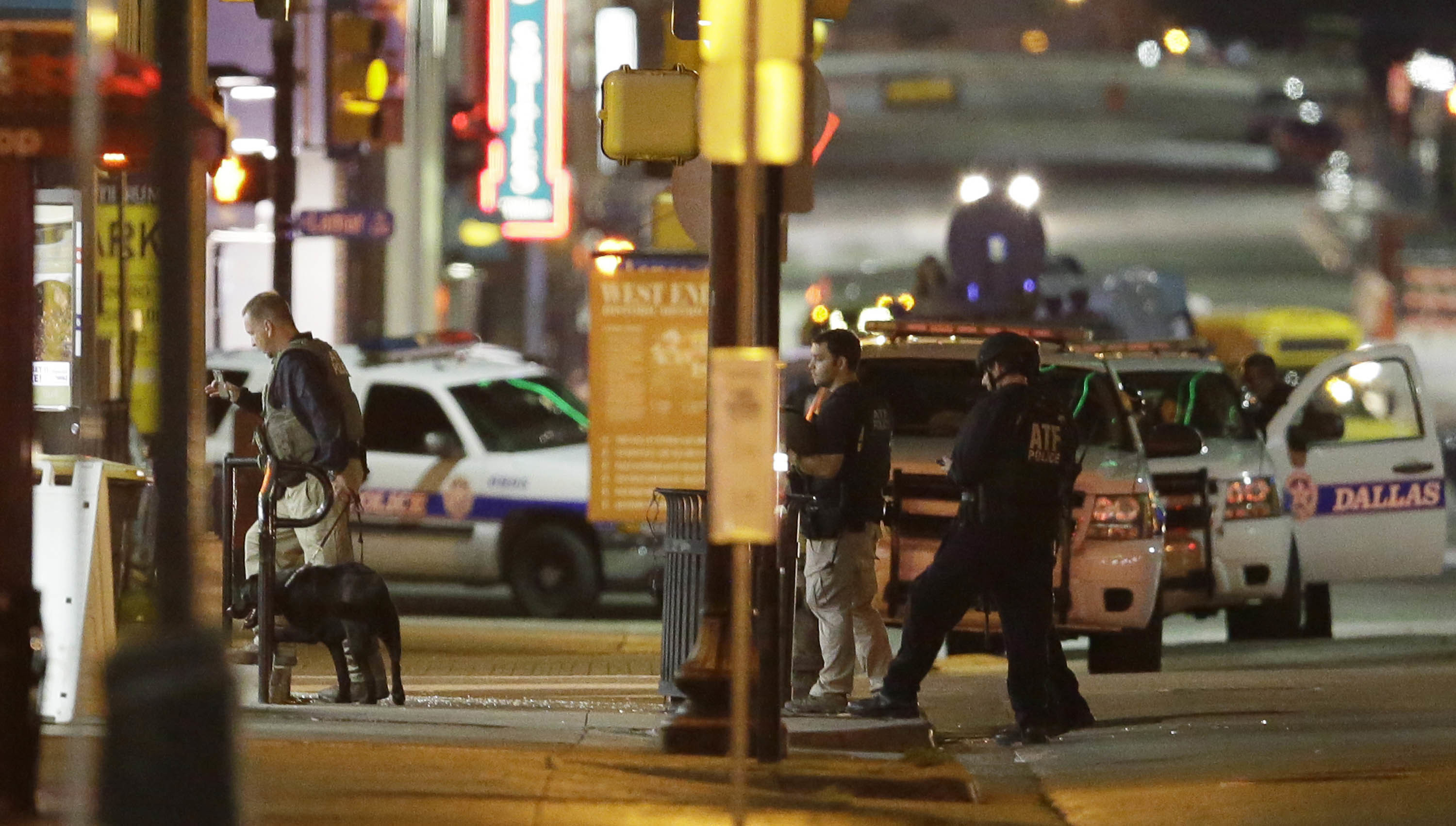 Law enforcement sweep the area after a shooting in downtown Dallas, Friday, July 8, 2016. At least two snipers opened fire on police officers during protests in Dallas on Thursday night; some of the officers were killed, police said. (AP Photo/LM Otero)