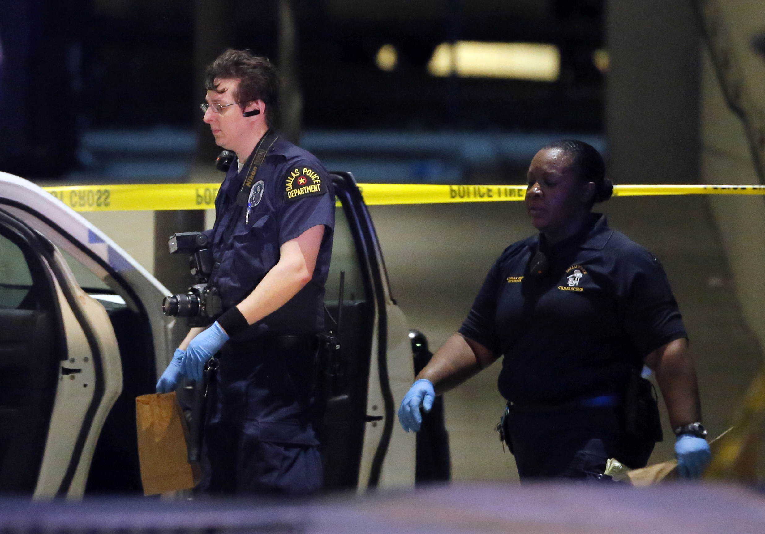 Dallas police crime scene investigators record evidence surrounding a police cruiser parked at the emergency room at Baylor University Medical Center, Friday, July 8, 2016, in Dallas. Snipers opened fire on police officers in the heart of Dallas on Thursday night, killing some of the officers. (AP Photo/Tony Gutierrez)