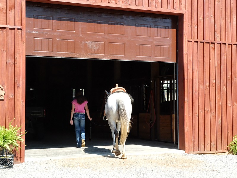 Holli Covey enters the barn after working her horse, Hank. Covey is a barrel racing champion in the state of Georgia.