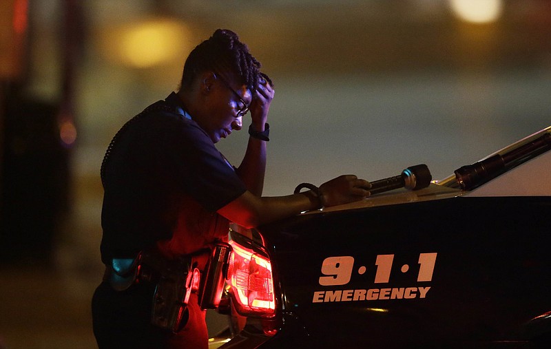 A Dallas police officer, who did not want to be identified, takes a moment as she guards an intersection in the early morning Friday after a shooting in downtown Dallas killed five members of the police force.