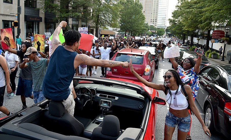 John Marshall, who was stuck in traffic heading home from work, gives a protester a fist bump on Marietta Street on Friday, July 8, 2016, in Atlanta. Thousands gathered in city streets to protest the recent shootings by police of black men. The group gathered outside the National Center for Civil and Human Rights before marching to Centennial Olympic Park and surrounding streets. (Brant Sanderlin/Atlanta Journal Constitution via AP)