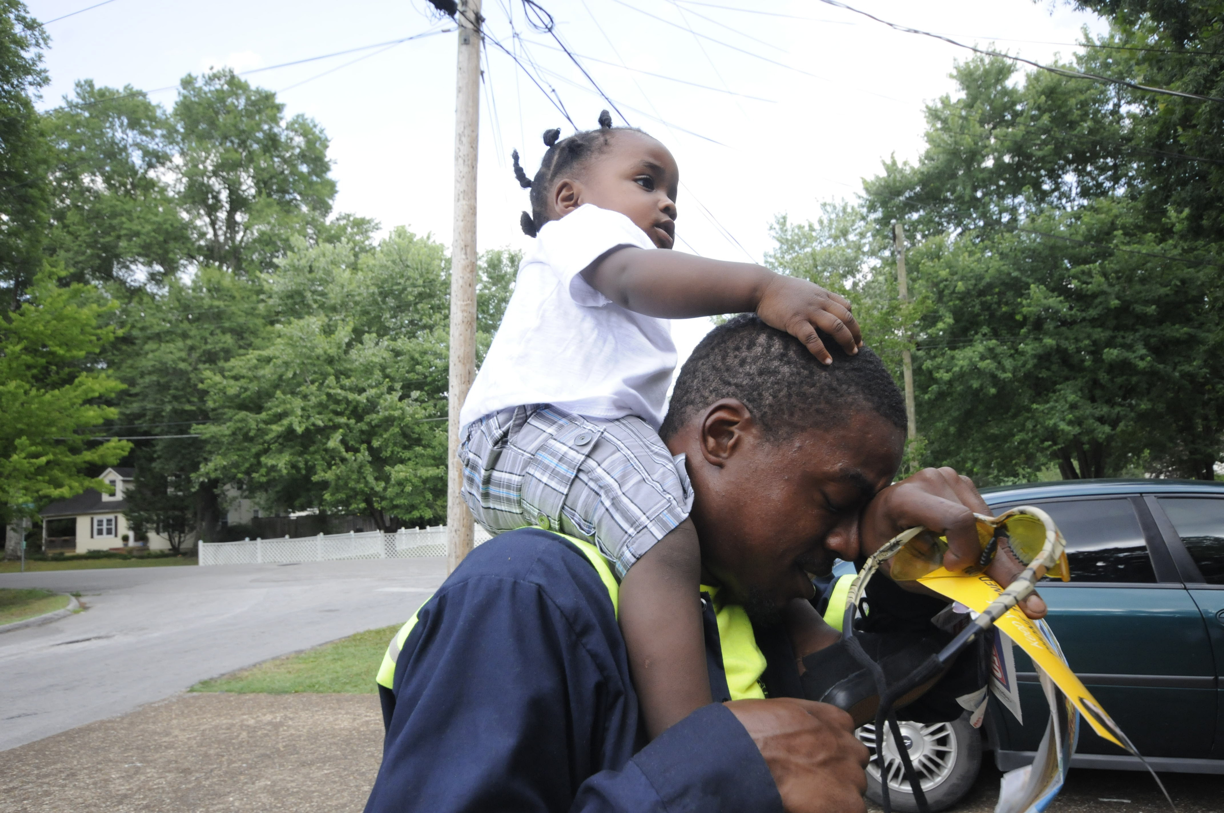 Upon arriving to his East Ridge residence, Jimmie Lebron Williams wipes his brow with his son, Kaptain Levi Williams, 1, riding atop his shoulders after work last week.
