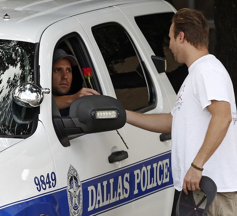 
              John Fife  hands a police officer guarding Jack Evans Police Headquarters a rose in Dallas on Friday July 8, 2016. Snipers opened fire on police officers in the heart of Dallas during protests over two recent fatal police shootings of black men.   (Nathan Hunsinger/The Dallas Morning News via AP)
            