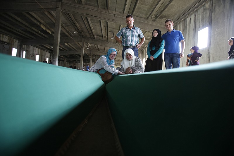 
              Bosnian Muslim women touch the coffin of a relative among 127 coffins displayed at THE memorial centre of Potocari near Srebrenica, 150 kms north east of Sarajevo, Bosnia, Saturday, July 9, 2016, prior to their burial scheduled for Monday. Thousands of Bosnians raised their hands in prayer Saturday as a truck bearing 127 coffins passed through the capital on its way to Srebrenica, where the newly identified victims of Europe's worst massacre since World War II will be buried on the 21th anniversary of the crime. (AP Photo/Amel Emric)
            