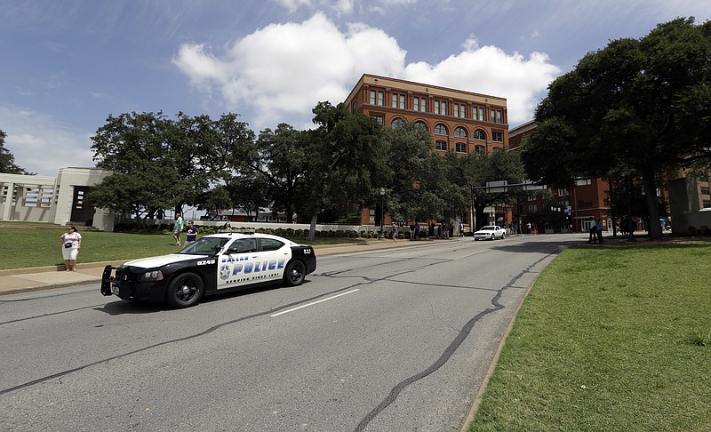 
              A Dallas patrol car passes Dealey Plaza in front of the Texas School Book Depository building, Saturday, July 9, 2016, in Dallas. After five police officers were killed in a shooting Thursday, a city forever haunted by the assassination of John F. Kennedy is trying to not let the worst America attack on police since Sept. 11 define it again. (AP Photo/Eric Gay)
            