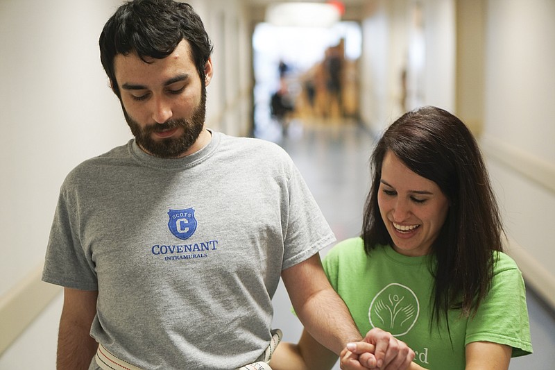 Staff Photo by Dan Henry / The Chattanooga Times Free Press- 6/27/16. Rachel Mahon, a physical therapist at the Shepherd Center, walks with Joel Elmore while at the rehabilitation center in Atlanta, Ga., on Monday, June 27, 2016. Elmore, a 22-year-old, contracted Guillain-Barre Syndrome in his senior year of college and was totally immobilized but is now going through physical rehab at Shepherd.