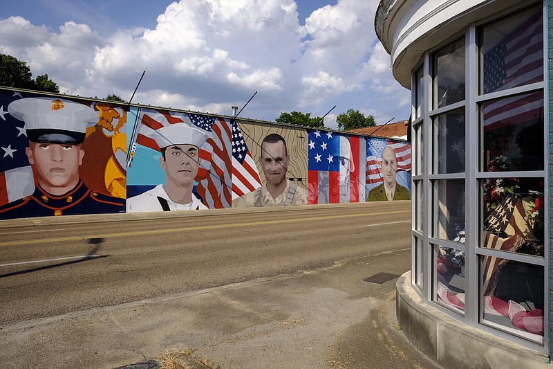 A flag is seen in the window of Joy's Flowers on McCallie Avenue across from a mural depicting servicemen killed in last July's attacks at area military facilities Friday, July 1, 2016, in Chattanooga, Tenn.