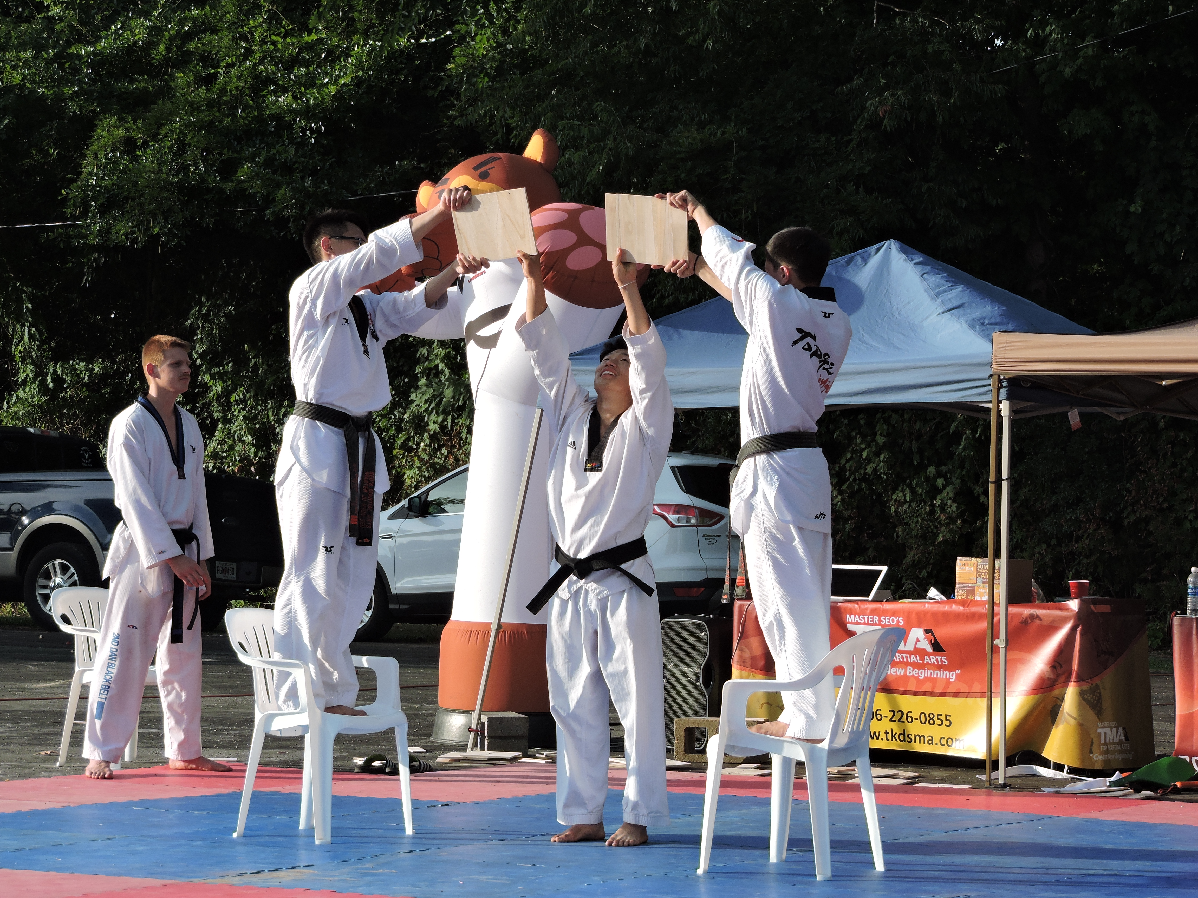 Master Seo's board breaking demonstrations drew a large crowd in between concert sets. Here, representatives set up two boards so that intern/instructor Kim, of Korea, can do a back flip and kick the boards to break them. From left are student Canyon Mantooth, instructor Calvin Hoeng, Kim and instructor Colton Mantooth.Staff photo by Katie WardMaster Seo's taekwondo students, instructors and an intern setup two boards, so that the intern can do a back flip and kick the boards to break them. From left are student Canyon Mantooth, Instructor Calvin Hoeng, of the LaFayette studio, intern/Instructor Kim, of Korea, and Master Seo's instructor Colton Mantooth, of the Dalton studio. It is part of the Master Seo's demonstrations at the city of LaFayette Park during the LaFayette Freedom Festival.