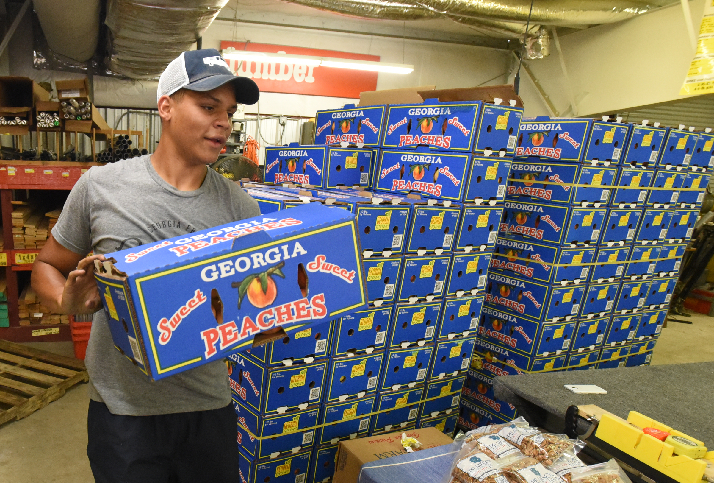 Corey Johnson, with the Peach Truck, hands out boxes of peaches to customers at East Ridge Hardware on Friday