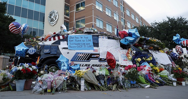 Two Dallas police patrol cars are covered with notes, flowers, balloons and other items as part of a makeshift memorial at the headquarters, Sunday, July 10, 2016, in Dallas. Five police officers were killed and several injured during a shooting in downtown Dallas Thursday night.