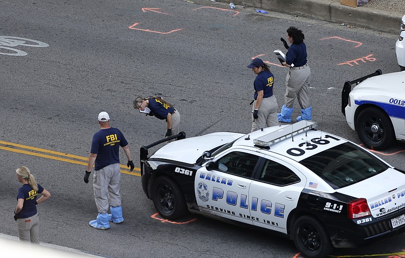 An FBI evidence response team works the crime scene, Sunday, July 10, 2016, where five Dallas police officers were killed Thursday, in Dallas. A peaceful protest over the recent videotaped shootings of black men by police turned violent Thursday night as gunman Micah Johnson shot at officers, killing five and injuring seven, as well as two civilians.