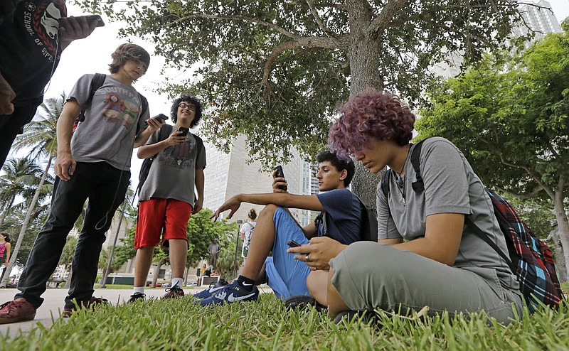 
              FILE - In this Tuesday, July 12, 2016 file photo, Pokemon Go players Ana Valentina Ojeda, right, and Jaeden Valdespino, second from right, check their smartphones as they look for Pokemon at Bayfront Park in downtown Miami as the "Pokemon Go" craze has sent legions of players hiking around cities and battling with "pocket monsters" on their smartphones. Nintendo suffered as a latecomer to smartphone games but is seeing the deep wealth of its franchise characters pay off with the success of “Pokemon Go,” even without a launch yet in Japan. The Japanese game maker was starting to look like a casualty of history until the game was launched in the U.S. earlier this month. Not anymore. (AP Photo/Alan Diaz, File)
            