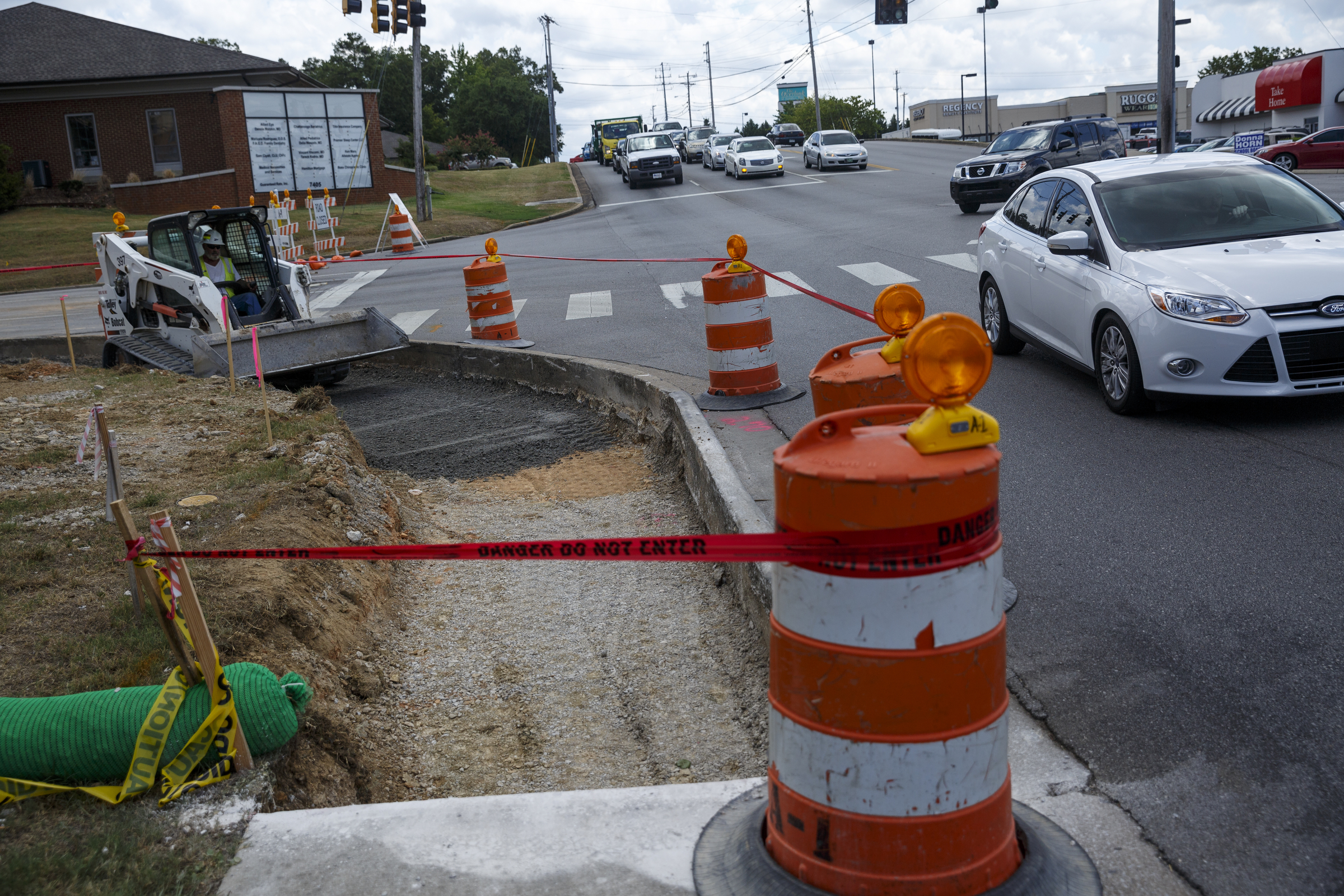 Cars pass on Shallowford Road as David Boyle uses an excavator on Gunbarrel Road between Shallowford Road and Preston Circle on Friday, July 15, 2016, in Chattanooga, Tenn. The section of road is closed to traffic for a widening project.