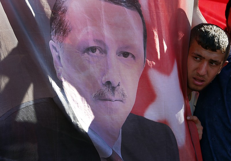 
              A Turkish man looks towards a portrait of Turkish President Recep Tayyip Erdogan during a protest against the military coup outside Turkey's parliament near the Turkish military headquarters in Ankara, Turkey, Saturday, July 16, 2016. Forces loyal to Turkey's President Recep Tayyip Erdogan quashed a coup attempt in a night of explosions, air battles and gunfire that left dozens dead Saturday. (AP Photo/Hussein Malla)
            