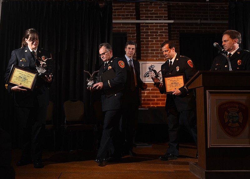 Staff photo by Tim Barber Chattanooga Mayor Andy Berke, back center right, observes Battalion Chiefs Lesley Morgan, left, Jeff Eldridge and Don Bowman as they receive the Meritorious Service Award at the Bessie Smith Hall in February.