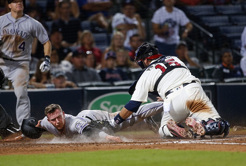 Colorado Rockies' Trevor Story (27) beats the tag from Atlanta Braves catcher A.J. Pierzynski (15) as he scores the go-ahead run on a Mark Reynolds ground ball during the ninth inning of a baseball game Saturday, July 16, 2016, Atlanta. Braves shortstop Erick Aybar was charged with an error. (AP Photo/John Bazemore)

