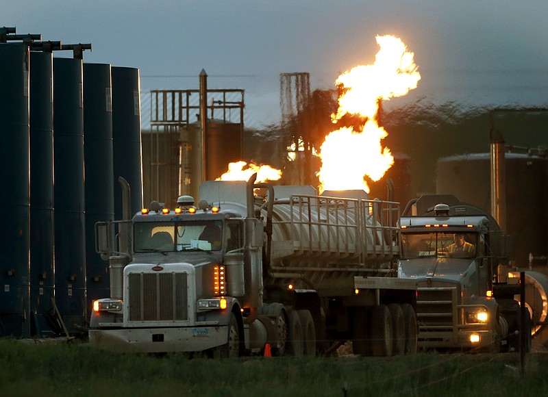 
              FILE - In this June 9, 2014 file photo, drivers and their tanker trucks, capable of hauling water and hydraulic fracturing liquid, line up near a natural gas burn off flame and storage tanks in Williston, N.D. According to a 2005-12 study at Geisinger Clinic in Pennsylvania, fracking may worsen asthma in children and adults who live near natural gas drilling sites. People with asthma are vulnerable to air pollution, and diesel exhaust from heavy truck traffic involved in the process may be one of the culprits, although the study doesn't prove what caused patients' symptoms. (AP Photo/Charles Rex Arbogast)
            