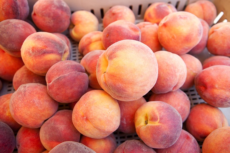 Delicious, farm fresh peaches are displayed in a crate at a farmers' market.
